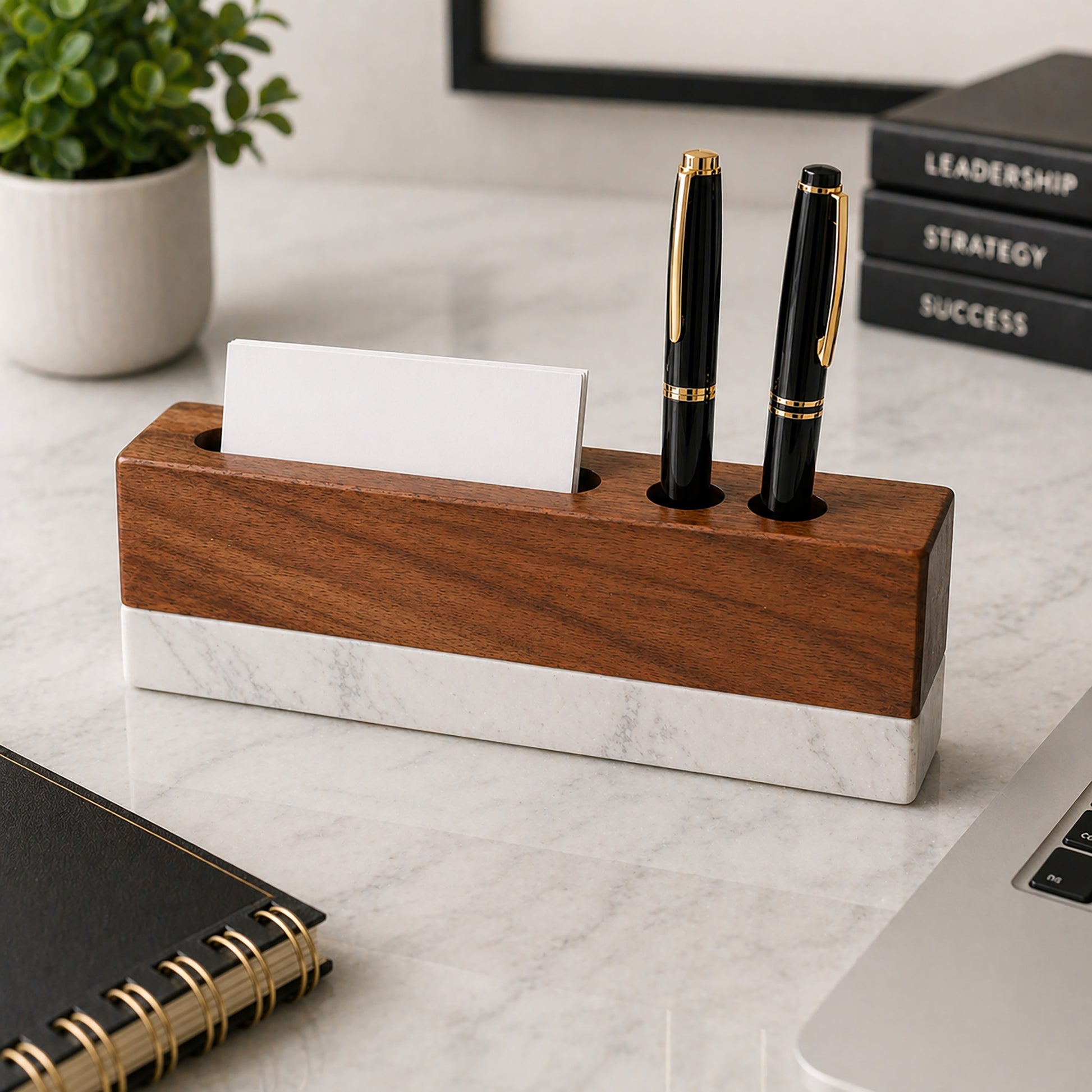 Wooden and marble pen holder with two black pens on a desk.