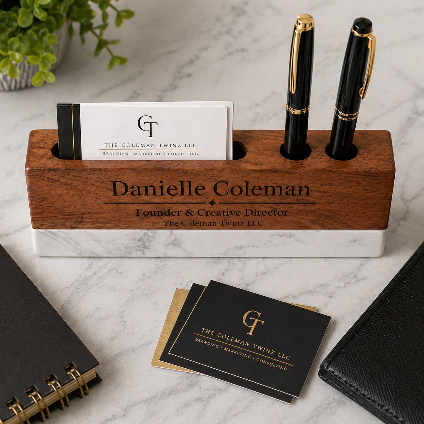 Wooden pen holder with personalized engraving on a marble surface with business cards and pens.