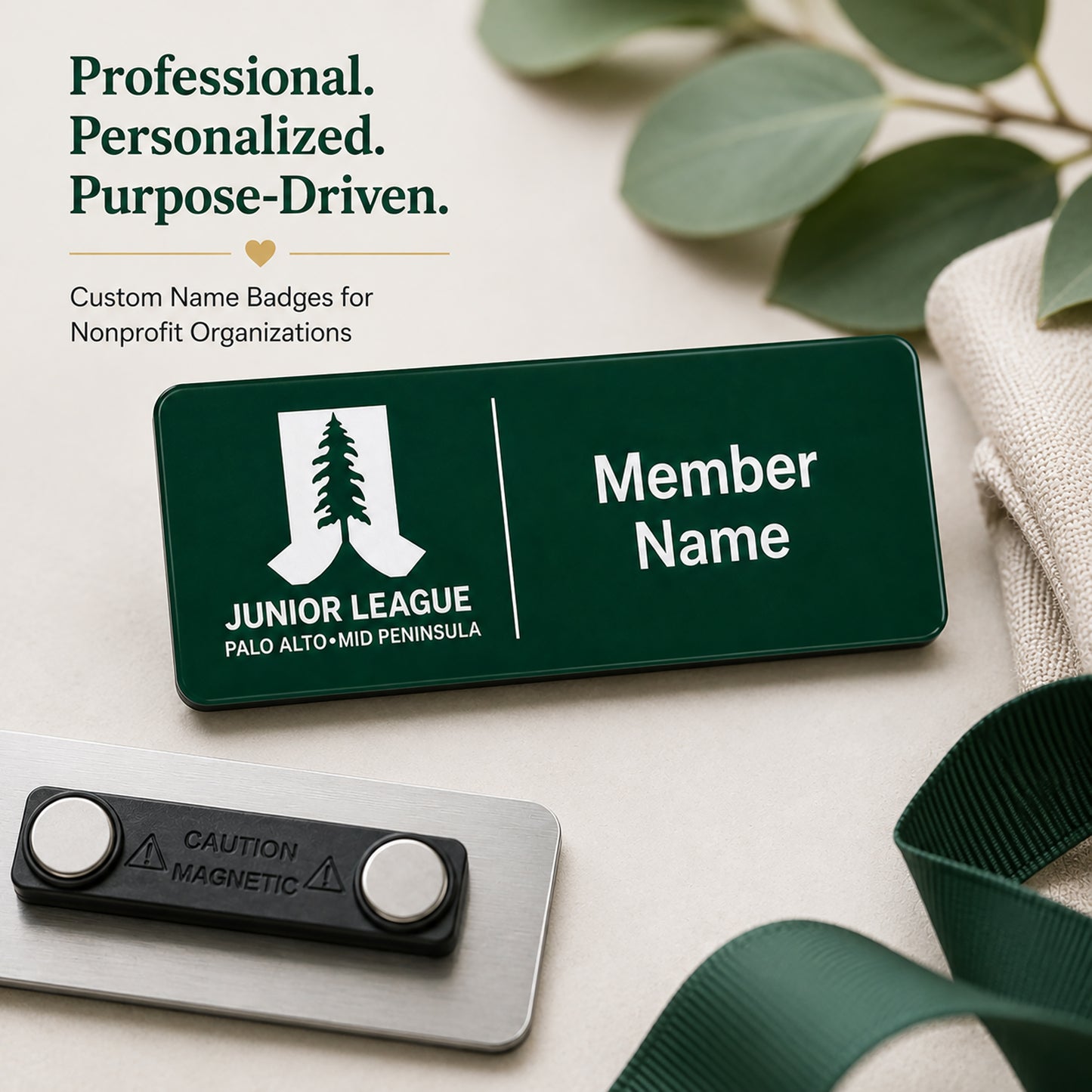 Professional personalized laser engraved name badge for Junior League Palo Alto Mid Peninsula nonprofit organization with magnetic back shown on neutral background with eucalyptus greenery and green ribbon