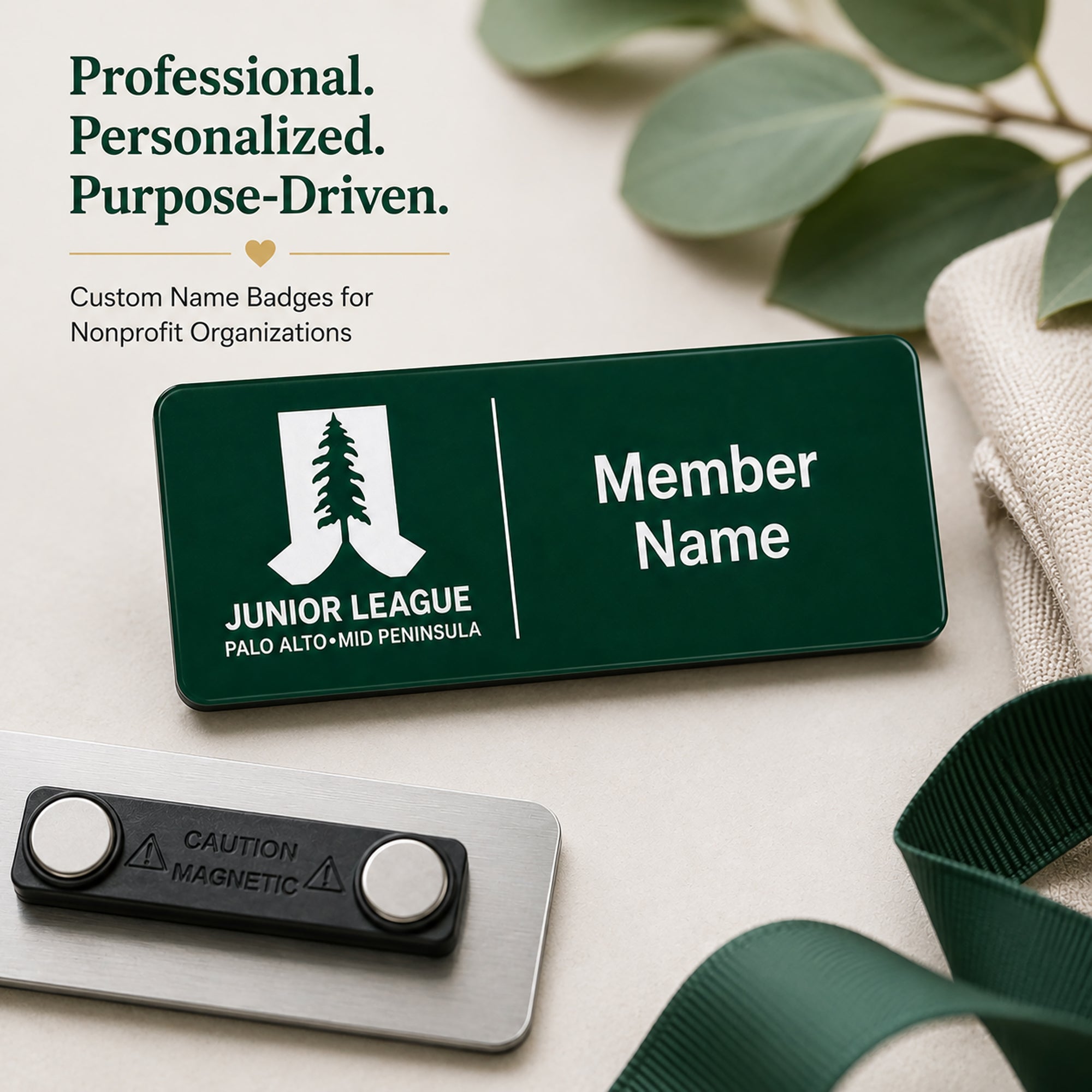 Professional personalized laser engraved name badge for Junior League Palo Alto Mid Peninsula nonprofit organization with magnetic back shown on neutral background with eucalyptus greenery and green ribbon