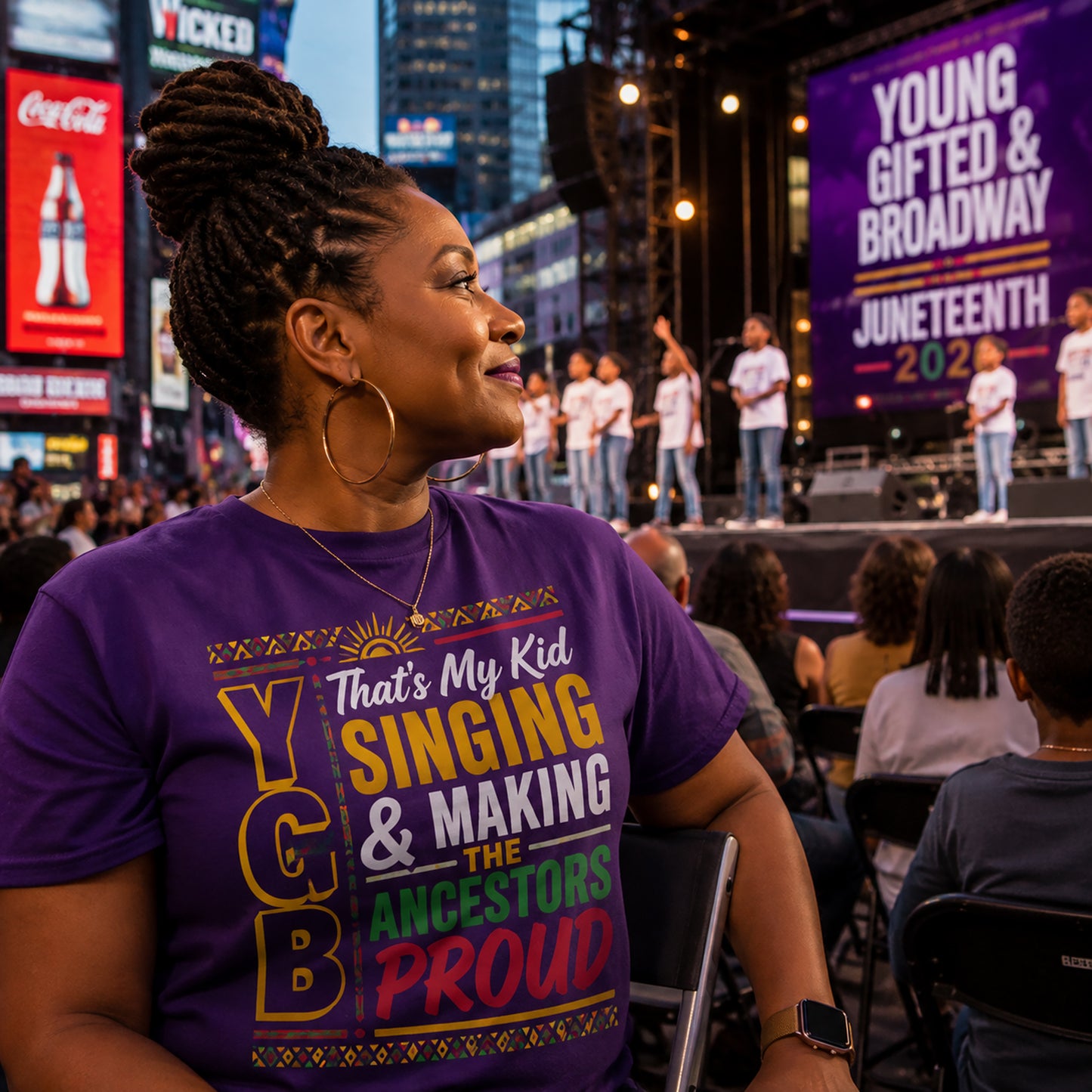 Person wearing a purple t-shirt with colorful text at an outdoor event with a stage and audience.