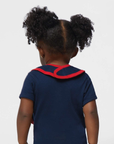 Baby back view wearing navy shirt with red collar trim