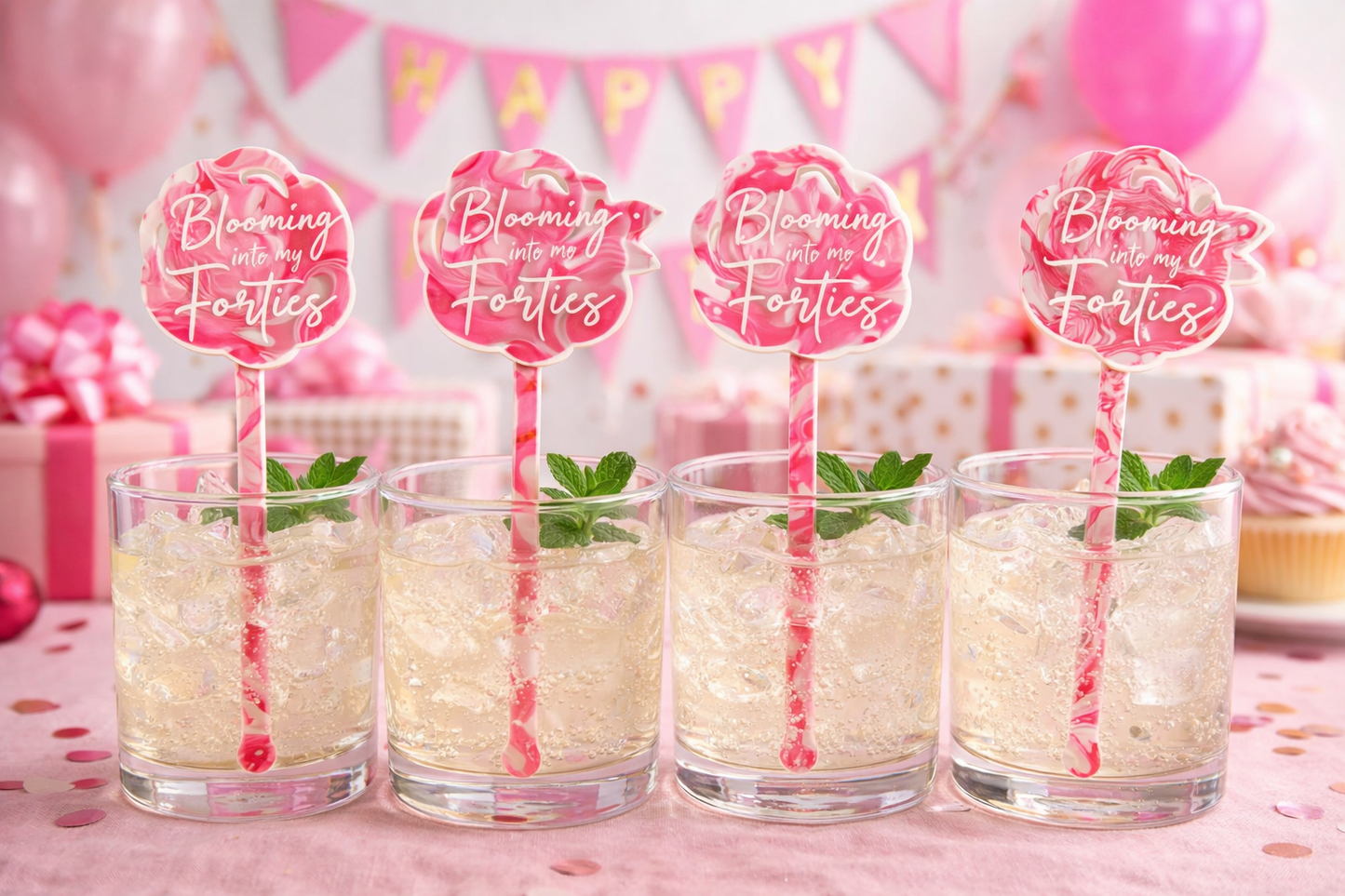 Four glasses of a creamy beverage with straws and 'Blooming Forties' signs on a pink background.