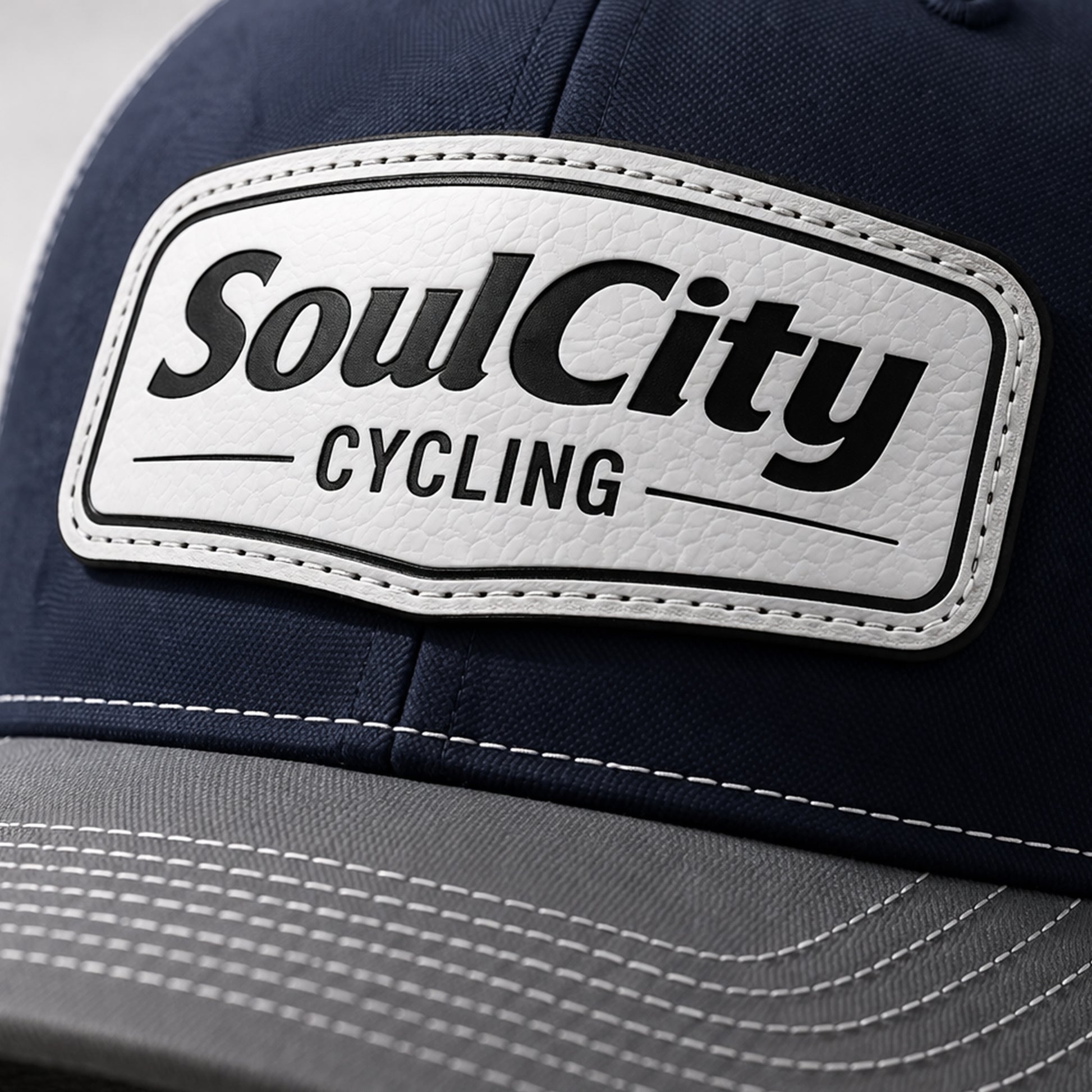 Navy and white SoulCity Cycling trucker hat on concrete surface with sunglasses and folded shirt