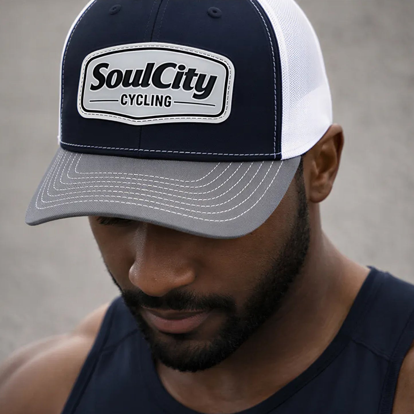 Athletic Black male wearing navy and white SoulCity Cycling trucker hat close-up cropped