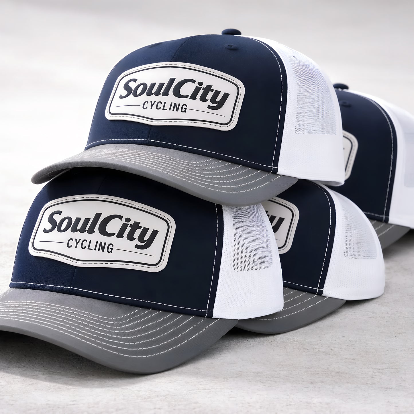 Stack of navy and white SoulCity Cycling trucker hats showing structure and design