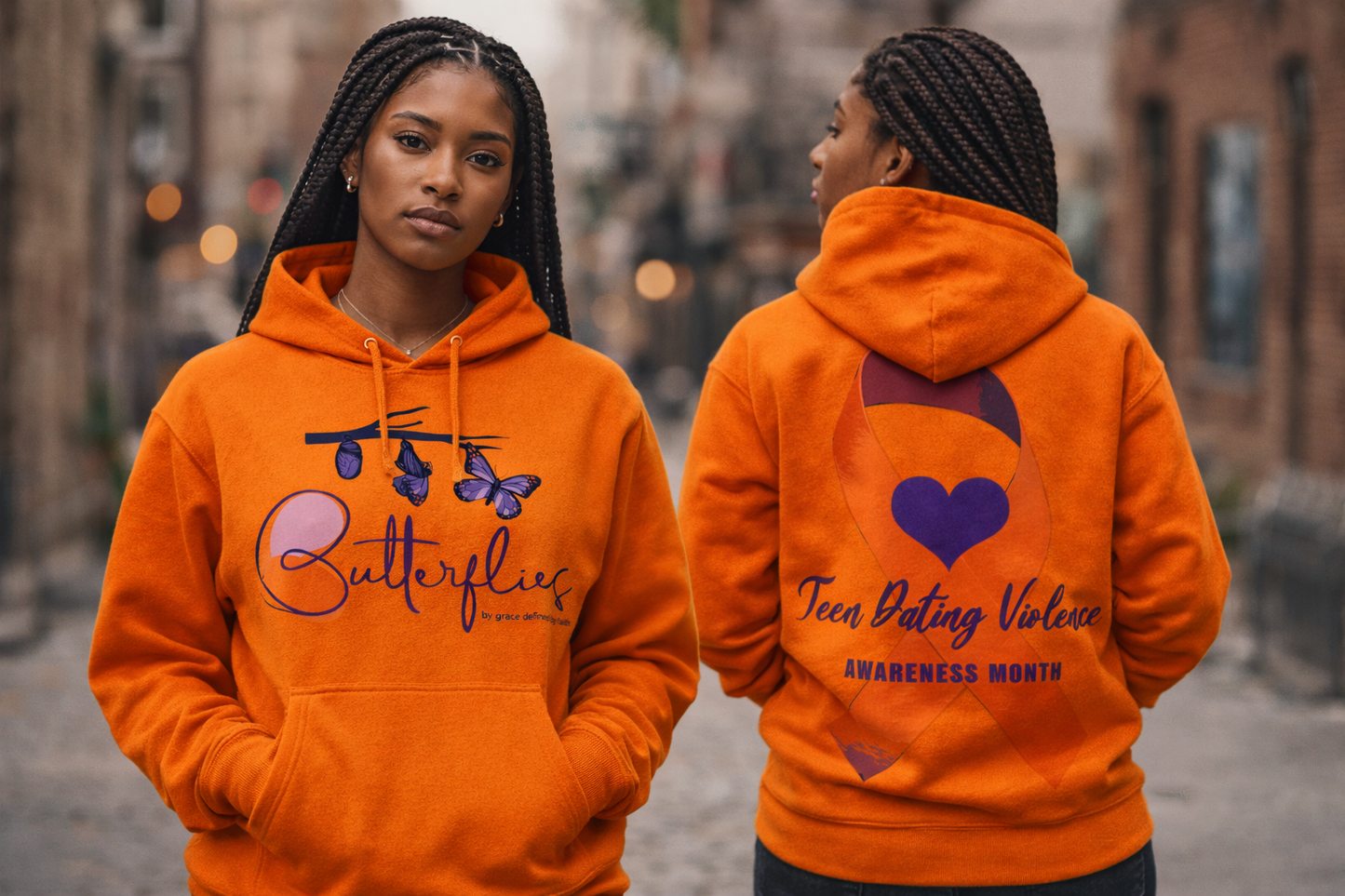 Two women wearing orange hoodies with visible text and graphics on a street.