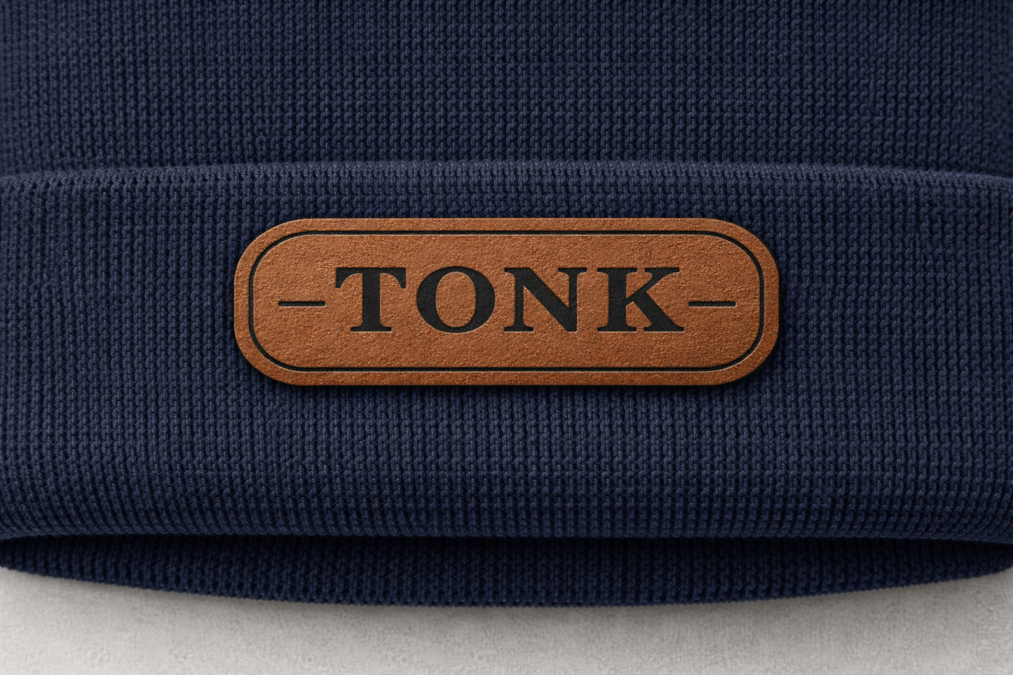 Navy blue fabric with a brown leather patch displaying the word 'TONK'.