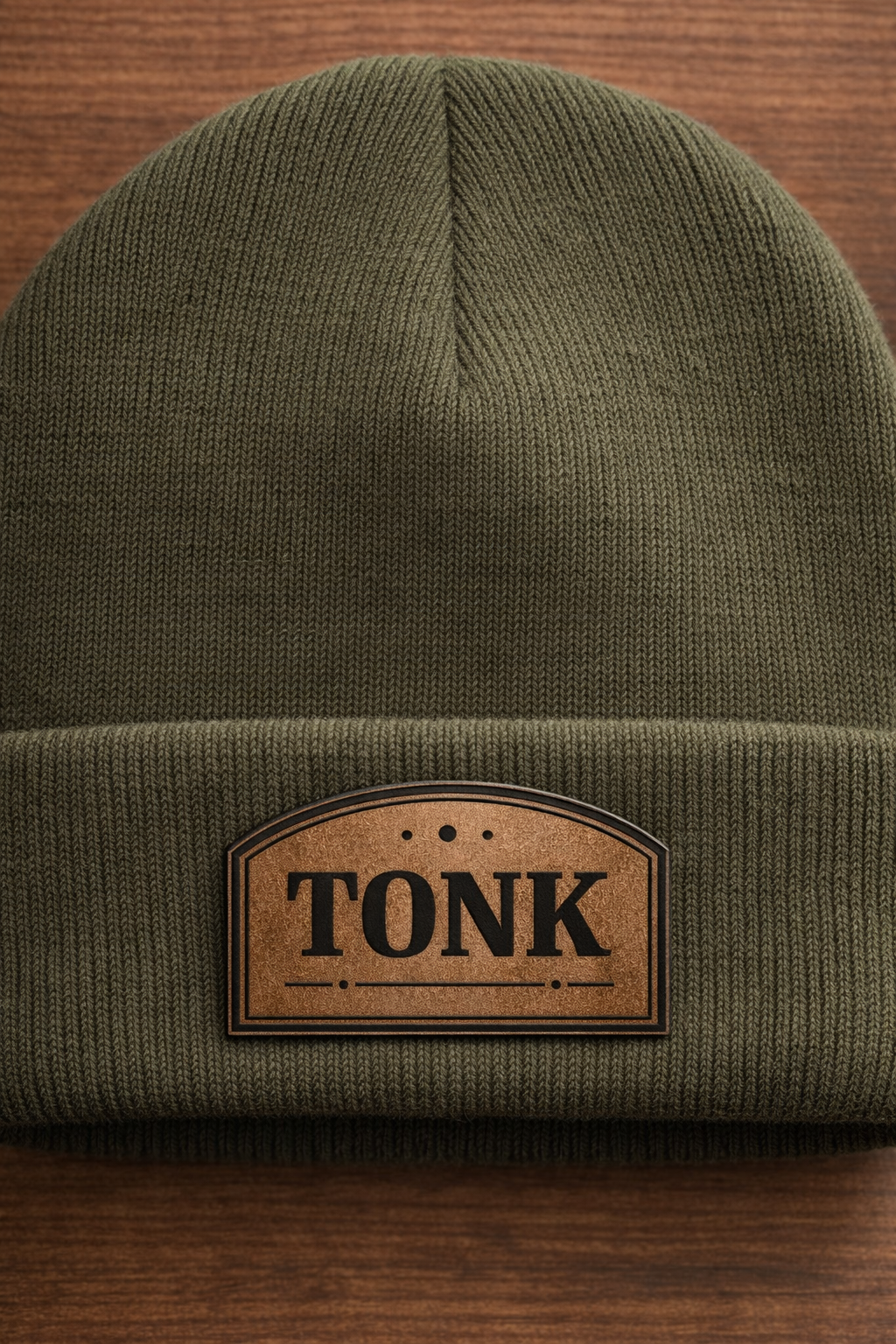 Green beanie with a brown leather patch labeled 'TONK' on a wooden surface