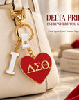 Delta Sigma Theta I Heart DST enamel charm attached to a cream handbag with polished gold-tone hardware