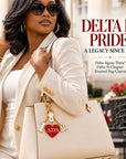 Stylish Black woman carrying a cream handbag with Delta Sigma Theta Delta Pi Chapter enamel bag charm