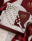 Delta Sigma Theta pearl lanyard necklace presented in luxury gift packaging with tissue paper and crimson ribbon