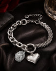 Officially licensed Delta Sigma Theta shield charm bracelet featuring a polished stainless steel heart charm displayed on black satin with a crimson rose and luxury perfume bottle.