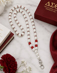 Flat lay of Delta Sigma Theta pearl beaded lanyard necklace with crimson accent beads and rhinestone spacers