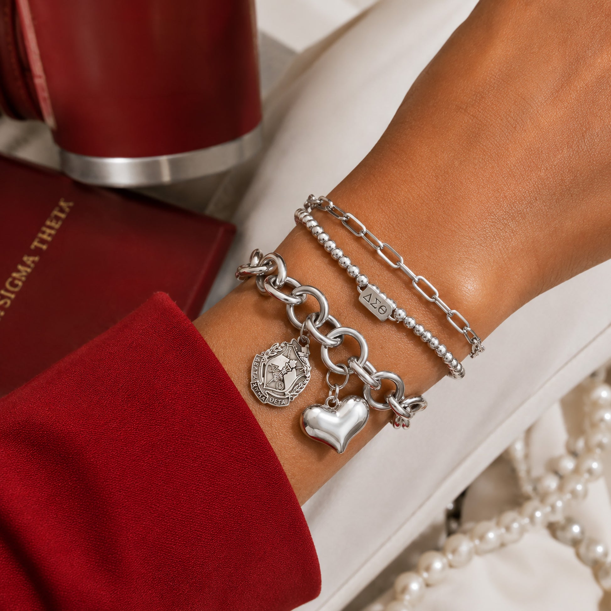 Delta Sigma Theta charm bracelet layered with coordinating silver bracelets for everyday sorority style.