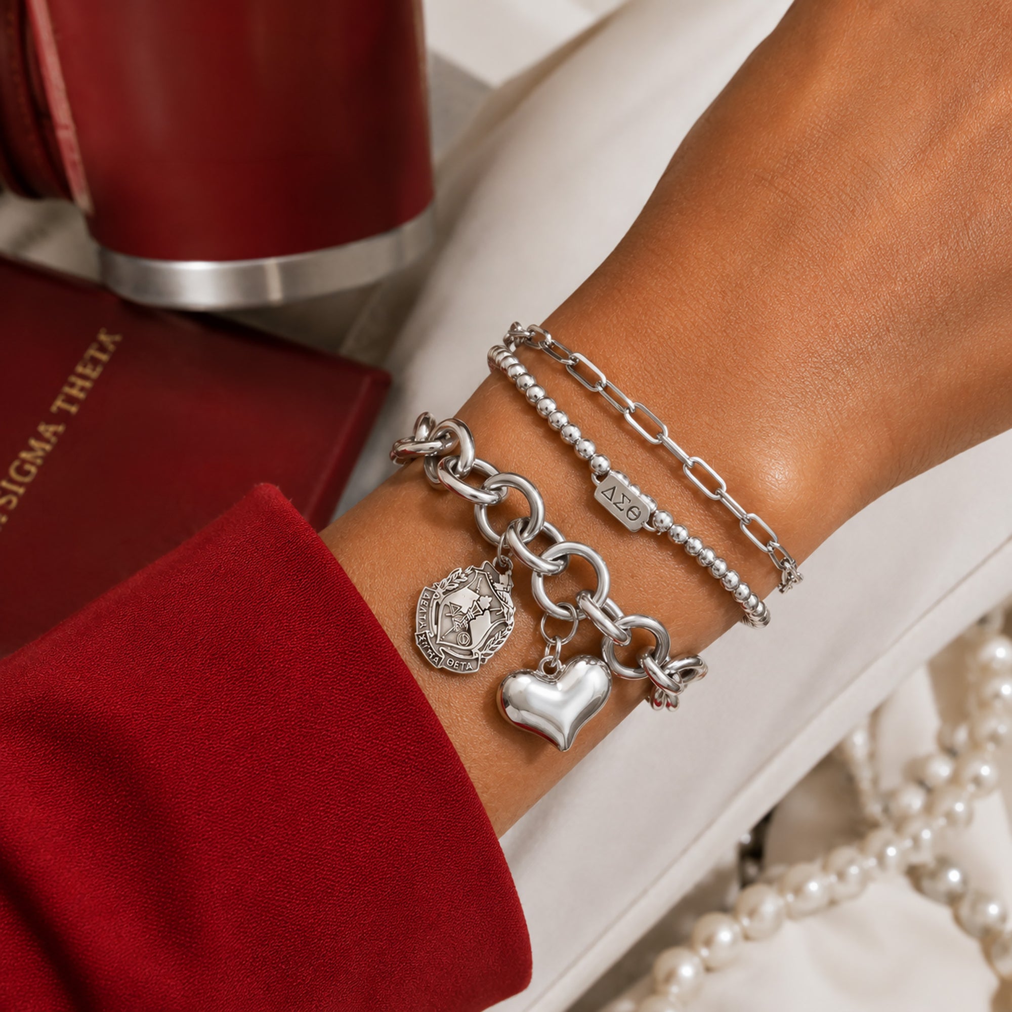 Delta Sigma Theta charm bracelet layered with coordinating silver bracelets for everyday sorority style.