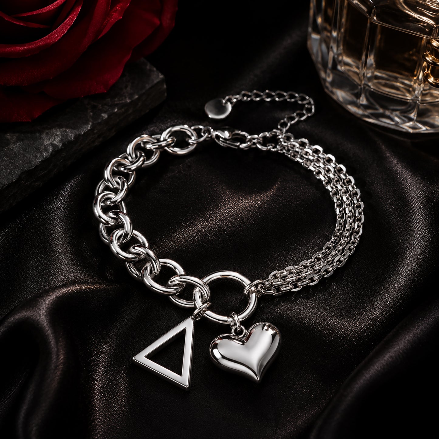 Officially licensed Delta Sigma Theta pyramid charm bracelet featuring a polished stainless steel heart charm displayed on black satin with a crimson rose and luxury perfume bottle.