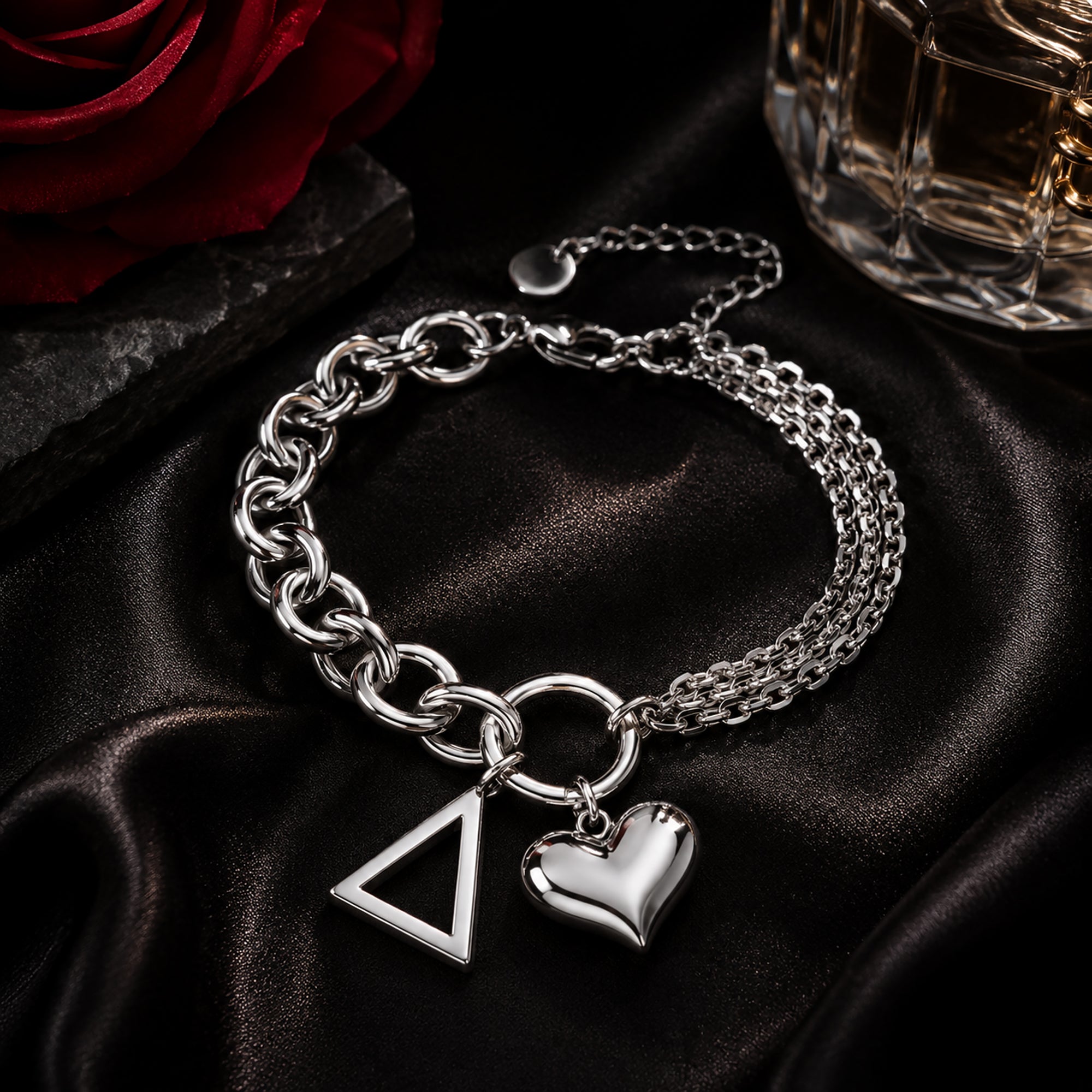 Officially licensed Delta Sigma Theta pyramid charm bracelet featuring a polished stainless steel heart charm displayed on black satin with a crimson rose and luxury perfume bottle.