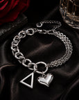 Officially licensed Delta Sigma Theta pyramid charm bracelet featuring a polished stainless steel heart charm displayed on black satin with a crimson rose and luxury perfume bottle.