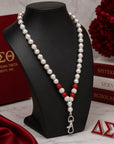 Angled view of Delta Sigma Theta pearl lanyard necklace featuring crimson rhinestone accents and silver clasp hardware
