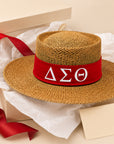 Straw hat with red band featuring Delta Sigma Theta Greek letters emblem