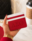 Crimson & White Delta Sigma Theta faux leather slim wallet styled with a luxury handbag, coffee, planner, and everyday accessories.