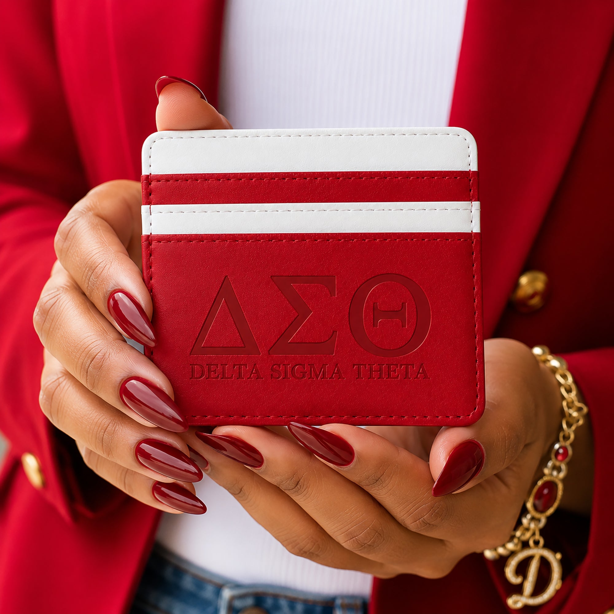 Woman holding the Crimson &amp; White Delta Sigma Theta faux leather slim wallet while wearing a red blazer and gold accessories.