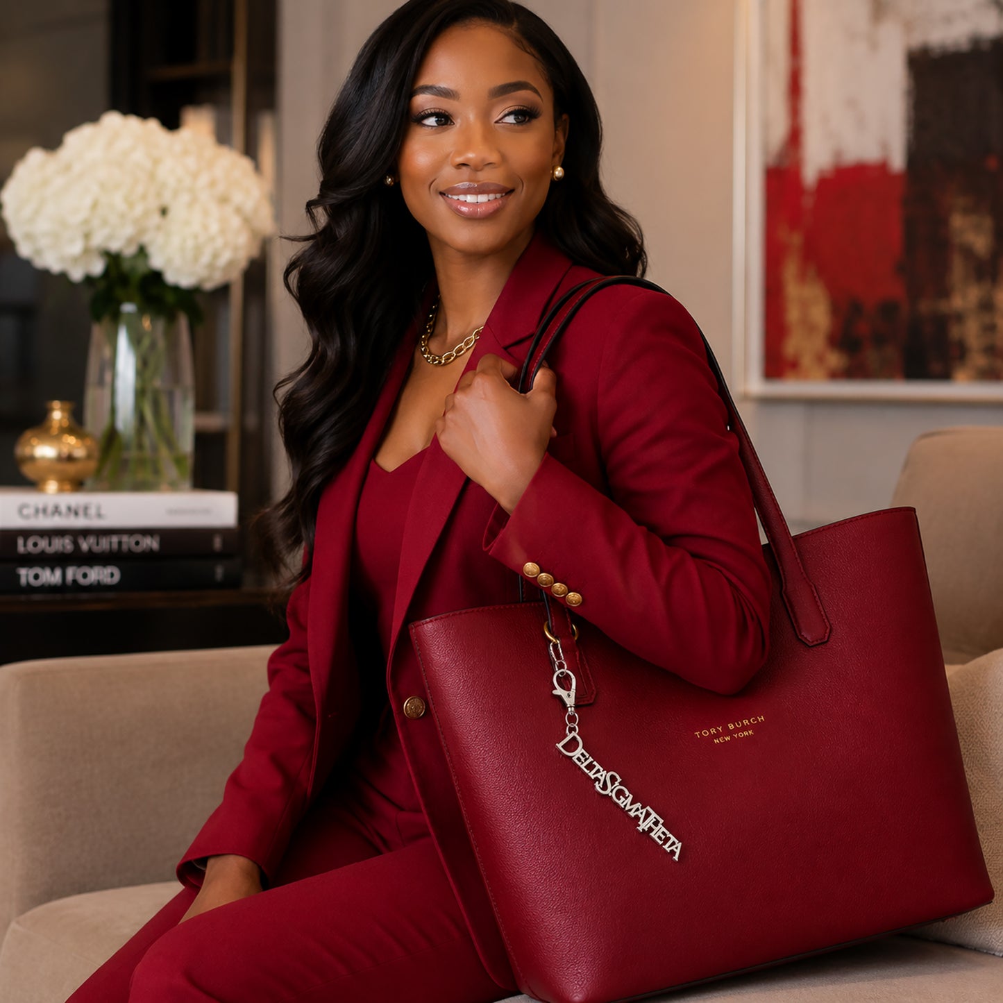 Woman in crimson blazer carrying red tote bag with Delta Sigma Theta silver Greek letter keychain charm