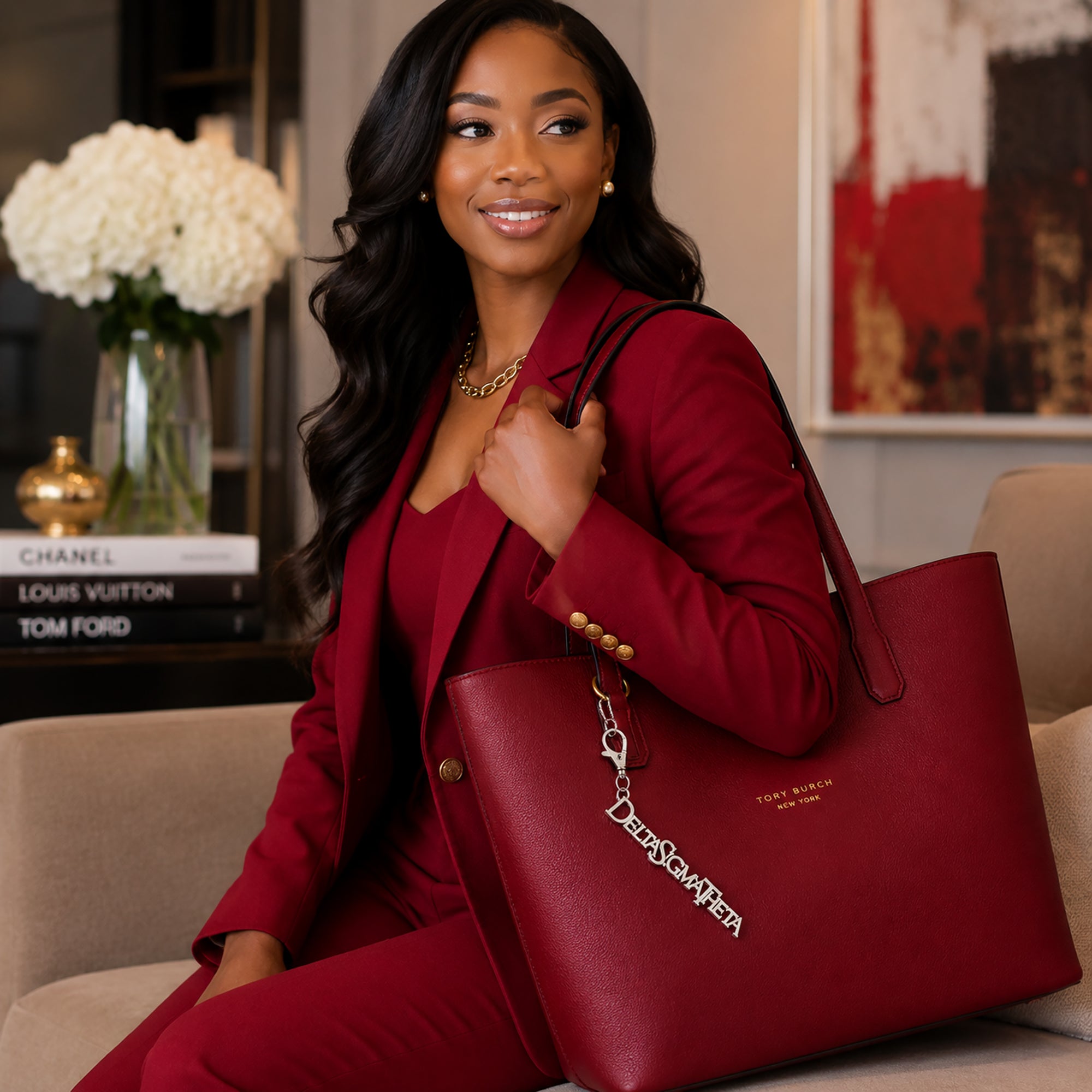 Woman in crimson blazer carrying red tote bag with Delta Sigma Theta silver Greek letter keychain charm