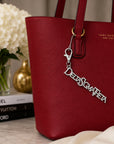 Delta Sigma Theta silver Greek letter bag charm attached to red tote bag