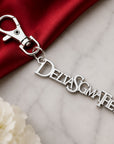 Close-up of Delta Sigma Theta silver Greek letter keychain charm clipped to red handbag with pearl bracelet