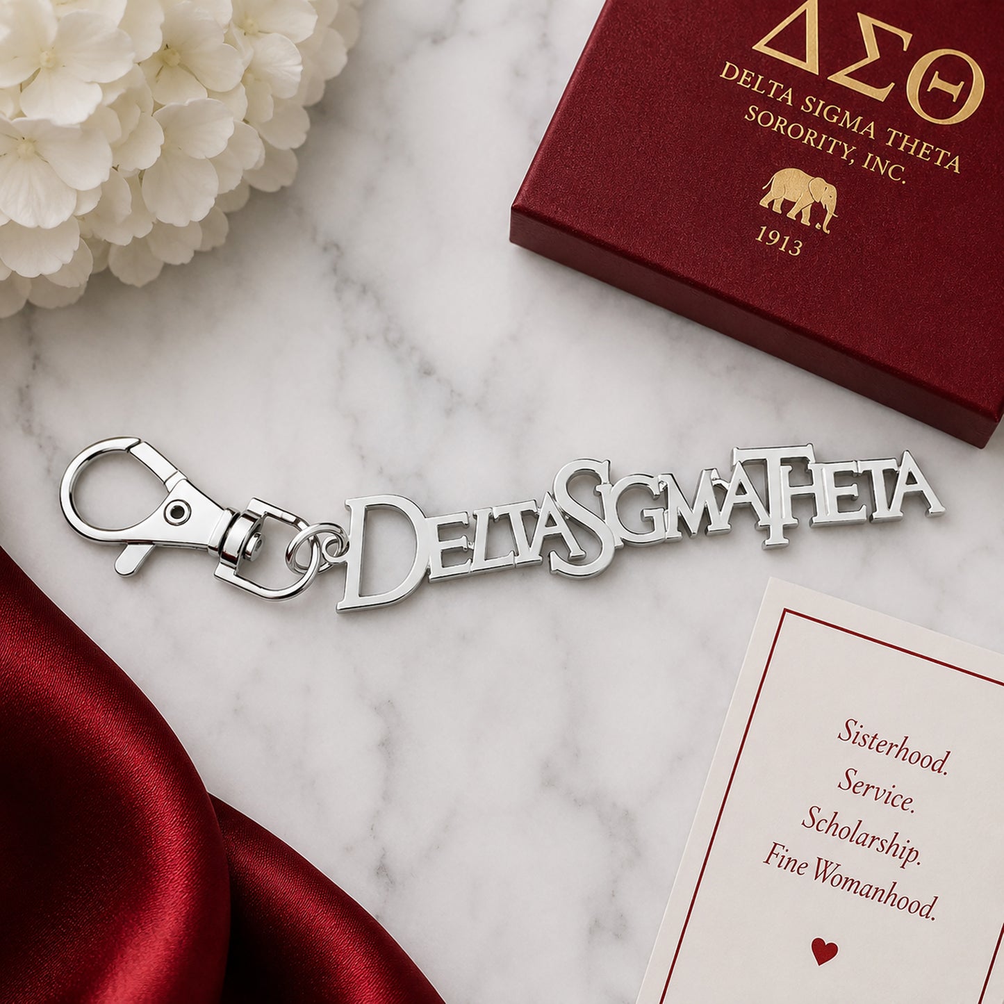 Delta Sigma Theta silver Greek letter keychain with lobster clasp on marble surface next to crimson gift box