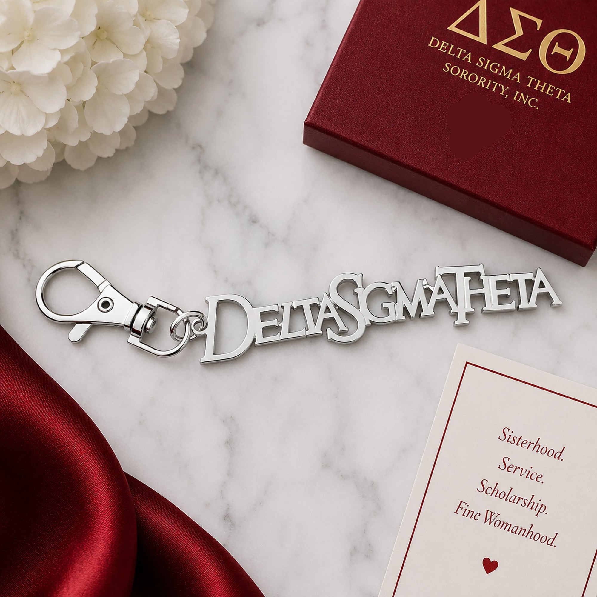 Delta Sigma Theta silver Greek letter keychain with lobster clasp on marble surface next to crimson gift box