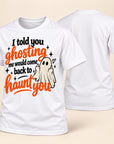 A white short-sleeve t-shirt with a Halloween graphic on the front, shown alongside a second view of the back. The graphic features the text 'I told you ghosting me would come back to haunt you' in black and orange lettering, along with a small cartoon ghost.