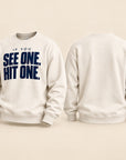 An off-white crewneck sweatshirt shown from both the front and back. The front features the text 'IF YOU SEE ONE, HIT ONE.