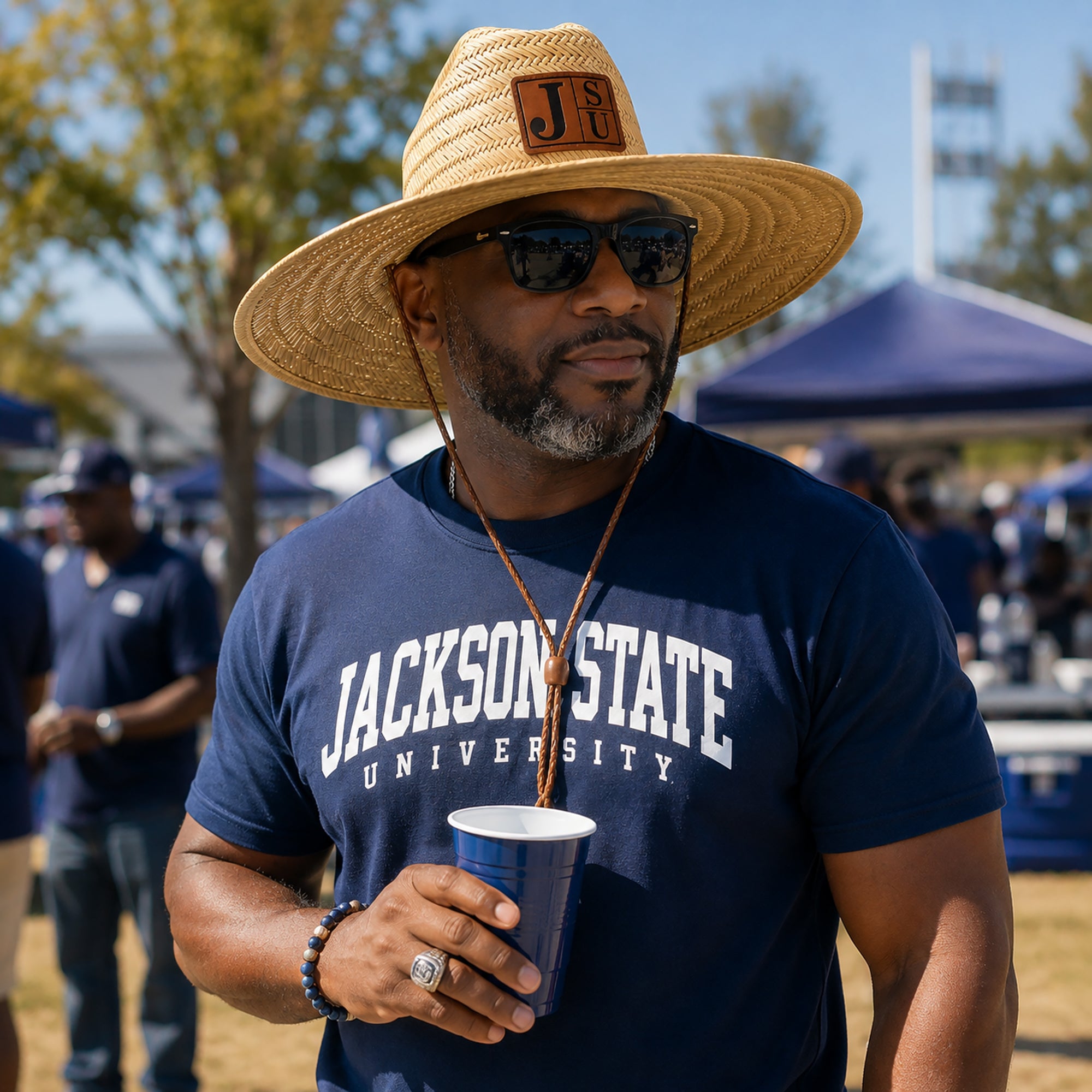 Man wearing Jackson State JSU wide brim straw lifeguard hat with walnut and black leatherette patch at an outdoor gameday event