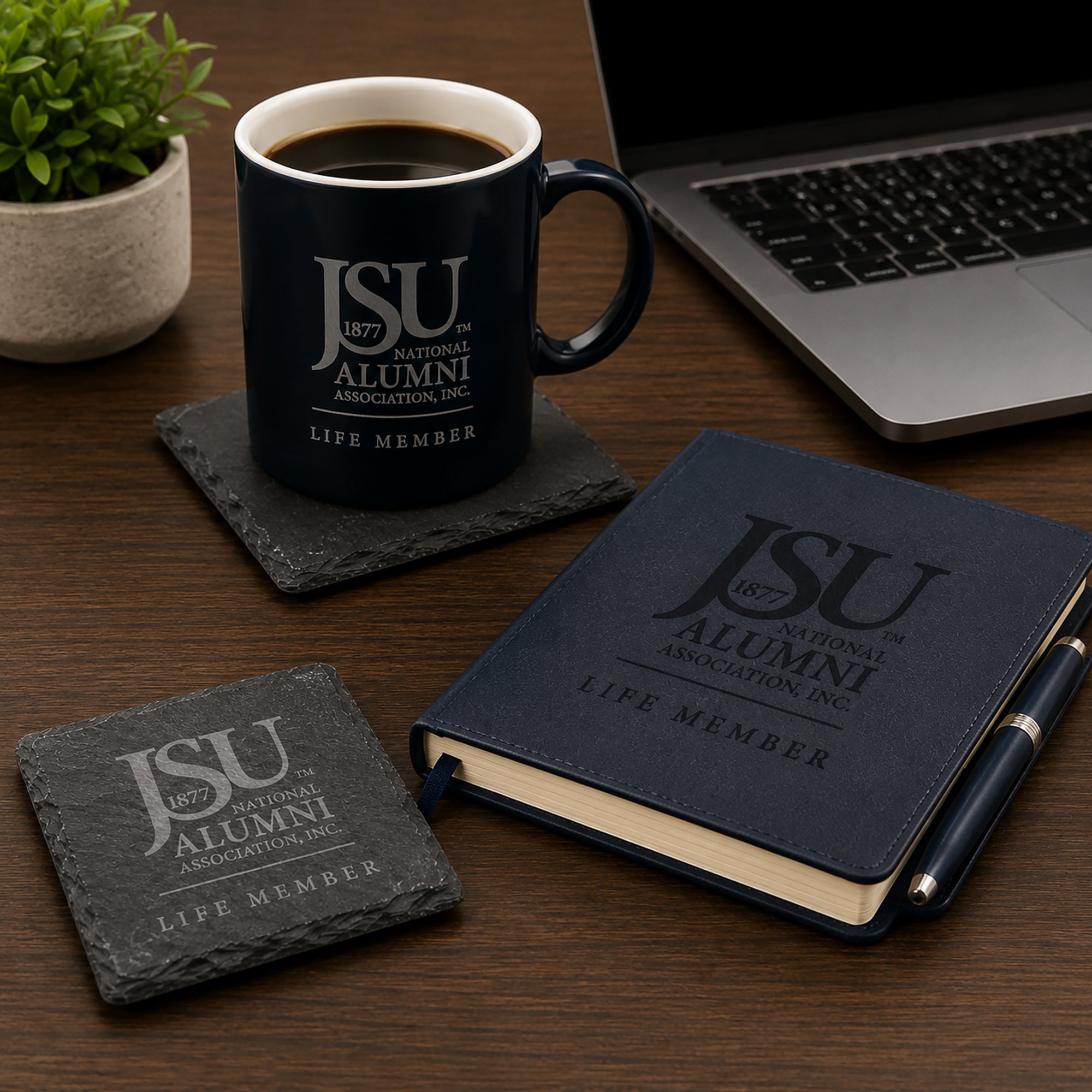 Jackson State University Life Member engraved slate coasters displayed on an executive desk beside a coffee mug, journal, laptop, and premium office accessories.