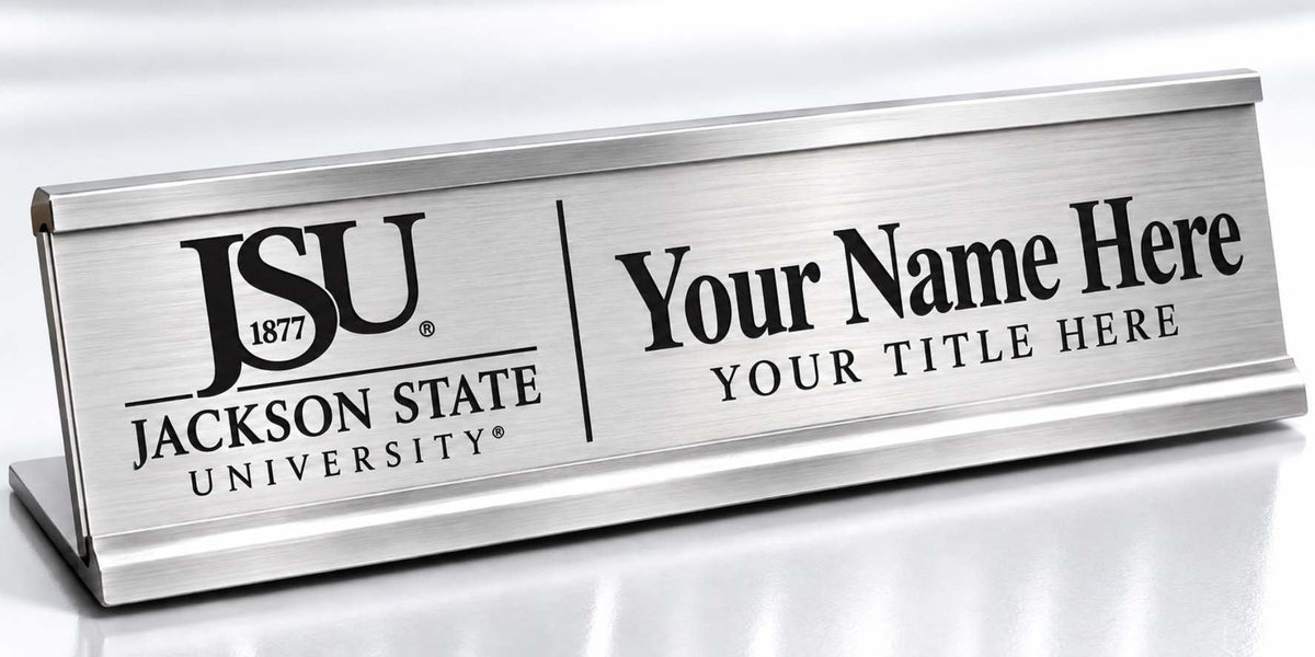 A silver metal desk nameplate with a brushed finish, featuring the Jackson State University logo on the left and customizable text reading 'Your Name Here' and 'YOUR TITLE HERE' on the right.