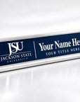 A rectangular desk nameplate with a silver metal frame and a dark blue front panel. The left side shows the white Jackson State University logo and text, while the right side has placeholder text reading 'Your Name Here' and 'YOUR TITLE HERE'.