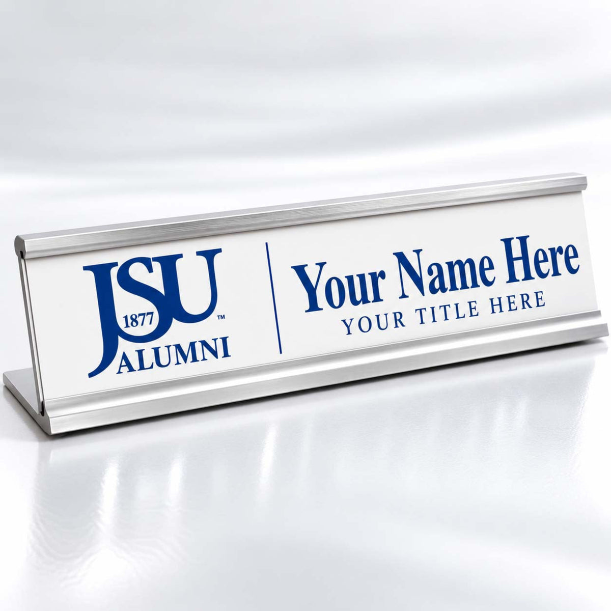 A silver aluminum desk sign with a white faceplate, featuring the blue 'JSU 1877 ALUMNI' logo and customizable blue placeholder text reading 'Your Name Here' and 'YOUR TITLE HERE'.