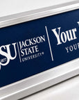 A close-up of a custom nameplate with a dark navy blue background and silver metal frame. The plate features the white text 'JSU JACKSON STATE UNIVERSITY' and placeholder text 'Your Na YOUR TI'.
