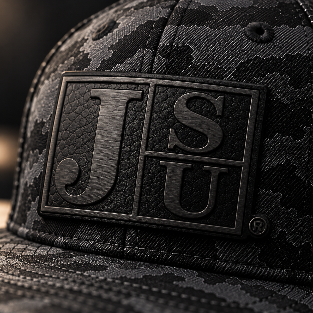 Close-up of tone-on-tone black Block JSU laser-engraved leatherette patch on Jackson State Black Camo New Era hat