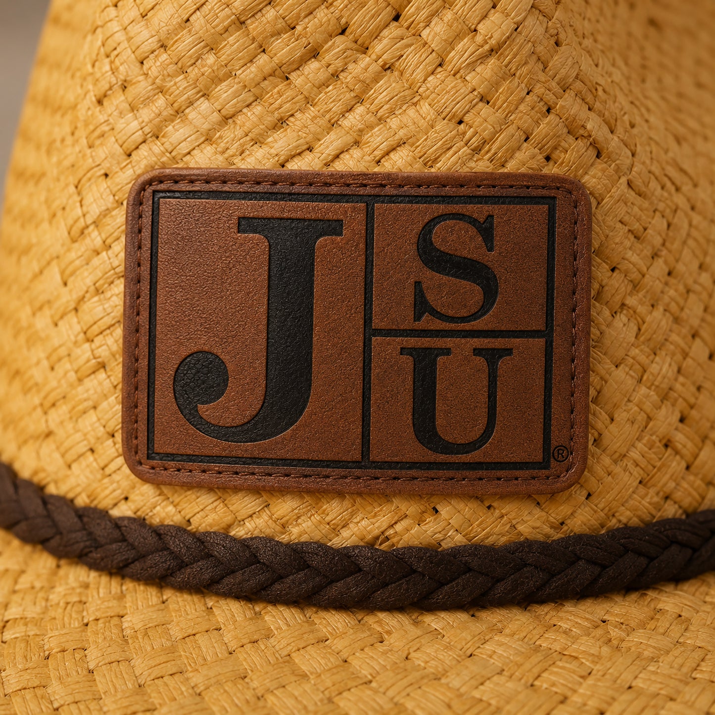Close-up of black engraved JSU Block Letter logo on walnut leatherette patch and raffia straw
