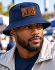 Black male model wearing Jackson State Tigers Dress Blue Navy outdoor bucket hat with walnut leatherette JSU patch