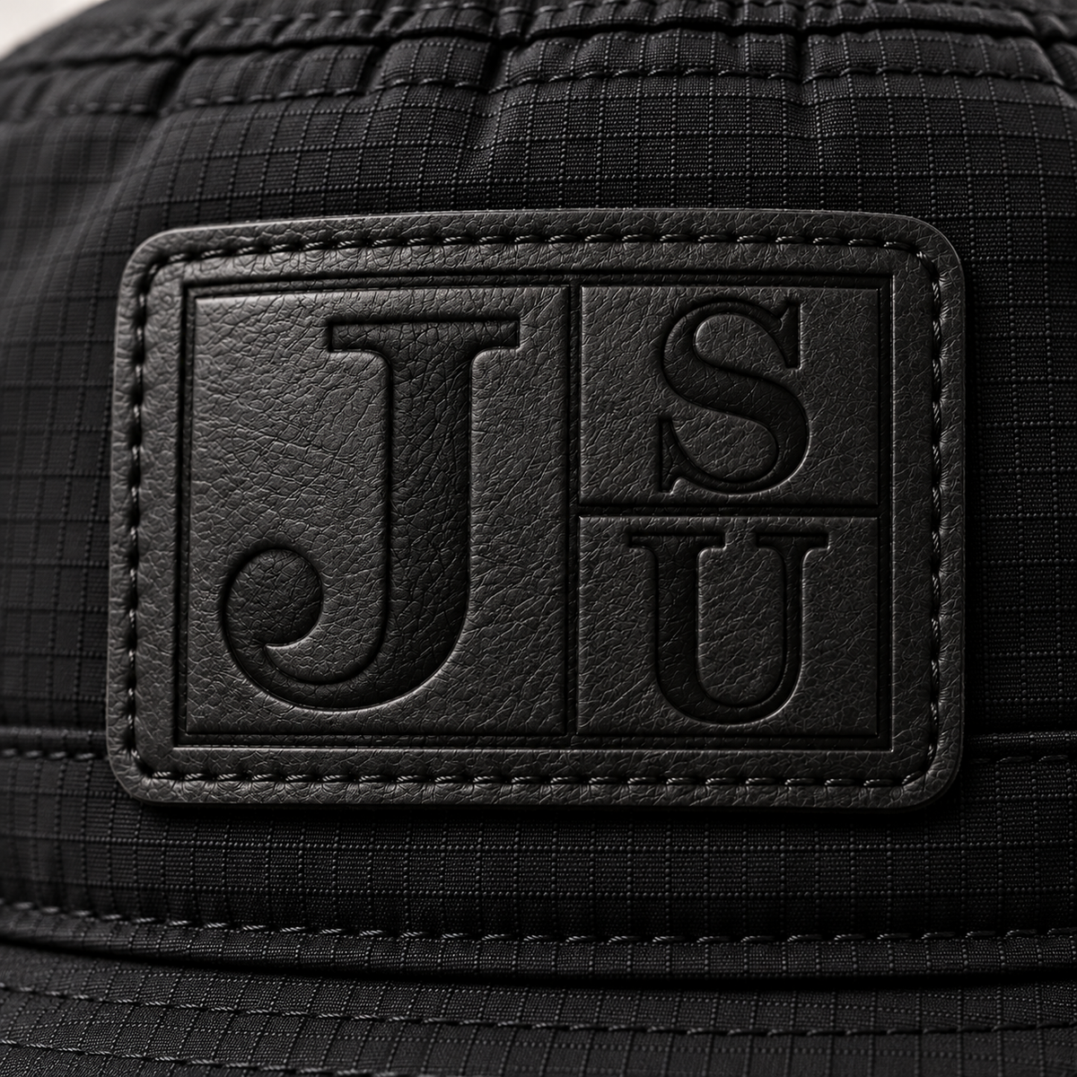 Close-up of tonal black leatherette Jackson State JSU patch on black bucket hat