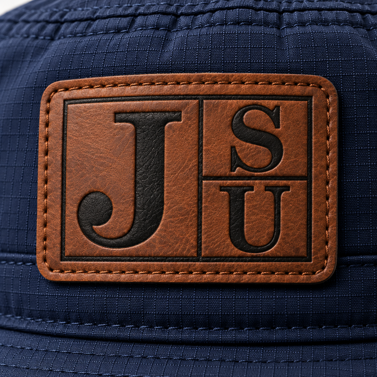 Close-up of walnut and black leatherette Jackson State JSU patch on Dress Blue Navy bucket hat