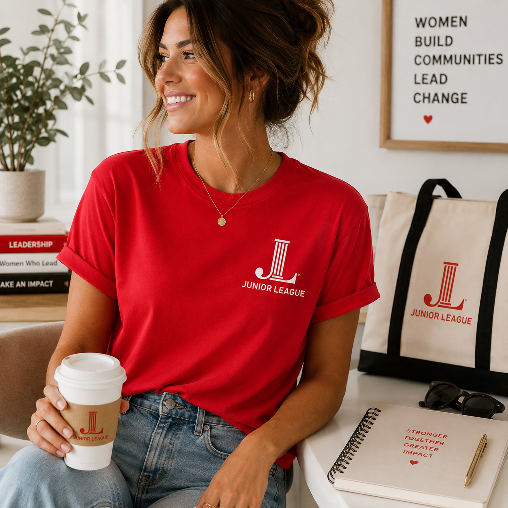 Woman wearing bright red Junior League Women Who Build Essential Tee styled with denim and leadership accessories