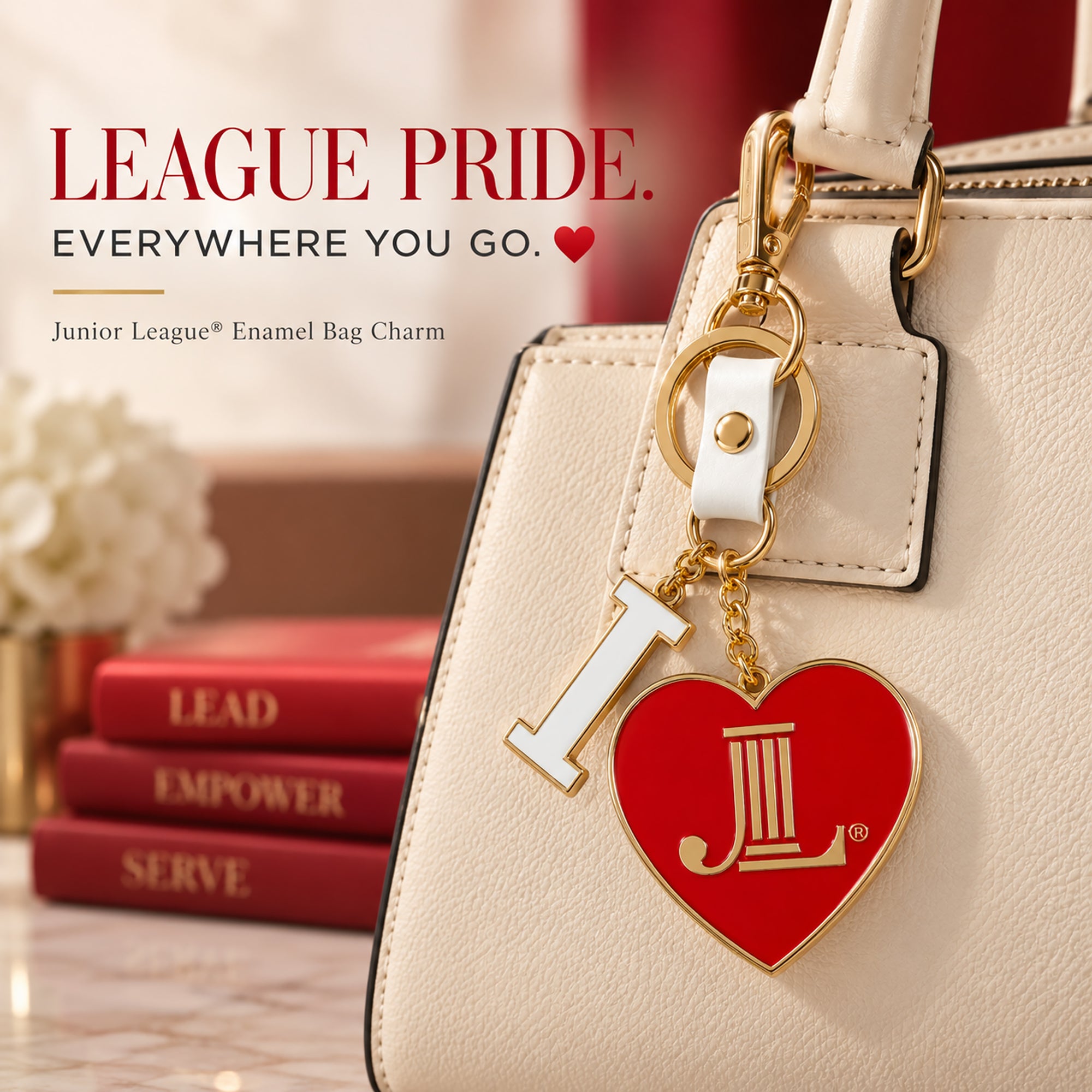 Junior League I Heart JL enamel bag charm attached to a cream handbag with gold-tone hardware