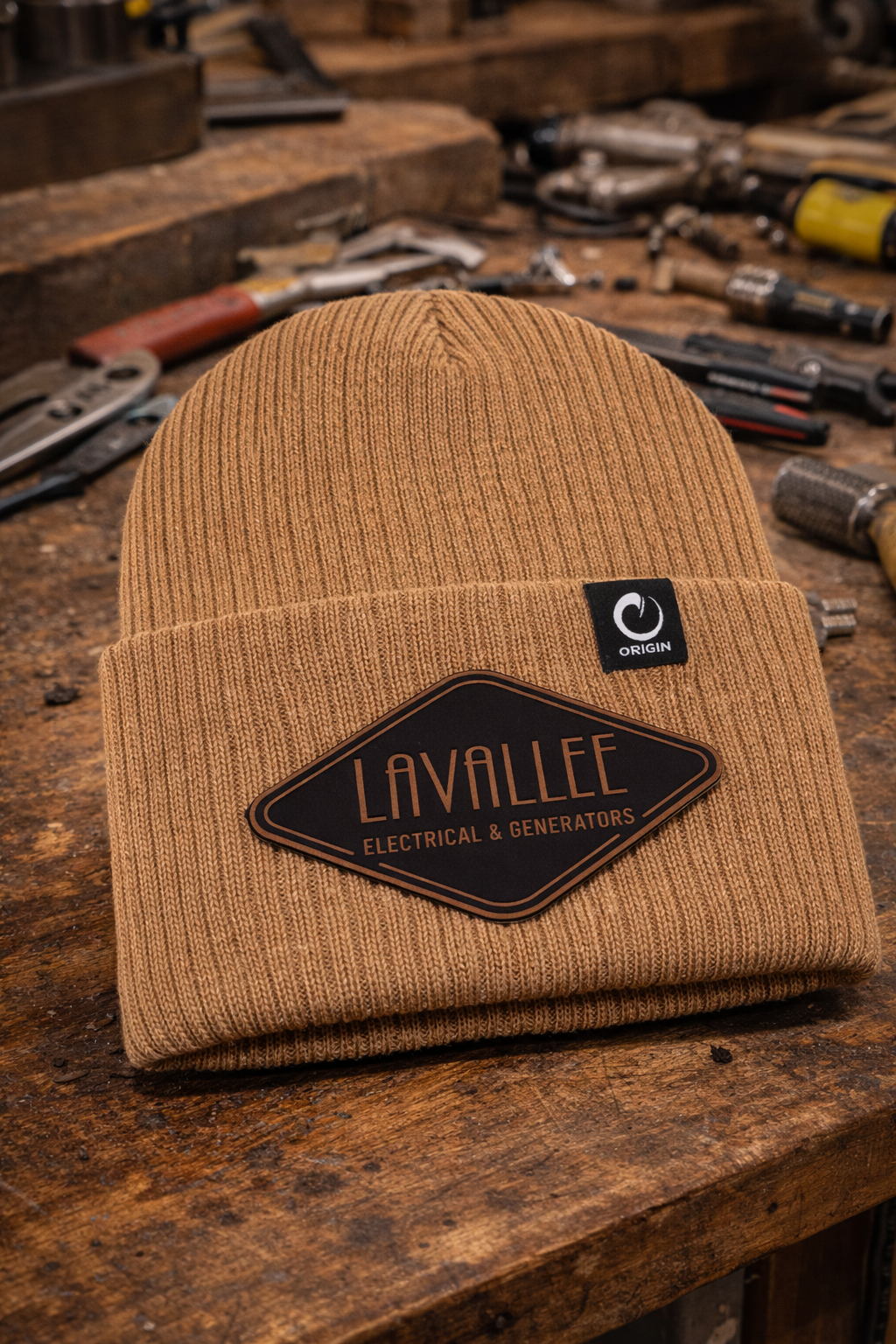 Custom Lavallee Electrical & Generators beanies featuring leatherette logo patch in black to copper shown on a workbench for electricians and generator technicians