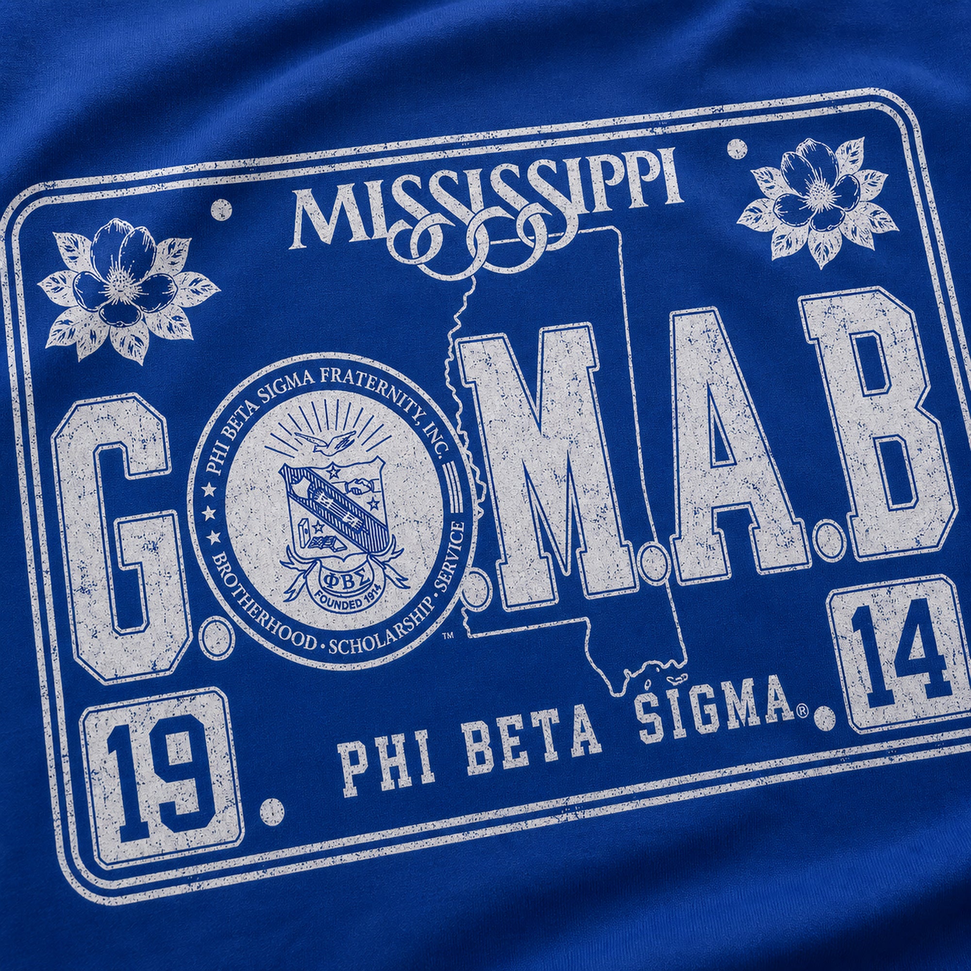 Close-up of royal blue T-shirt fabric with large G.O.M.A.B. Phi Beta Sigma print
